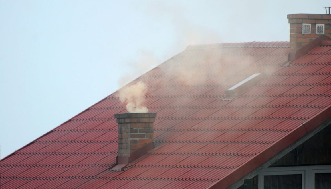Zanieczyszczony dym, wydobywający się z komina w domu jednorodzinnym