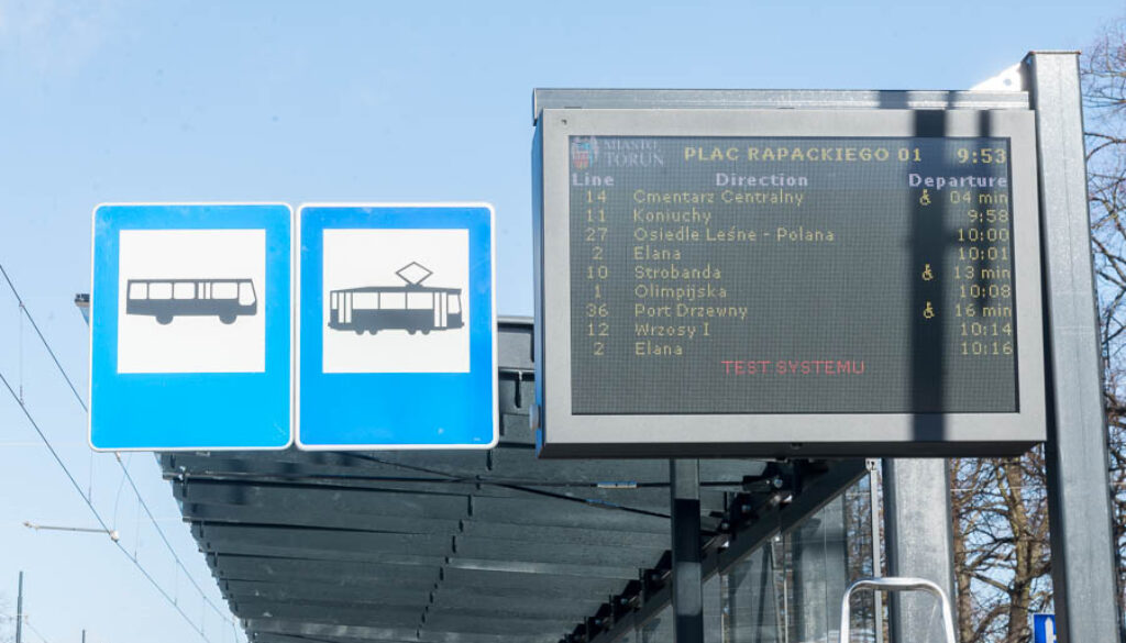 Tablica informacyjna z przyjazdami autobusów i tramwajów na przystanku w Toruniu