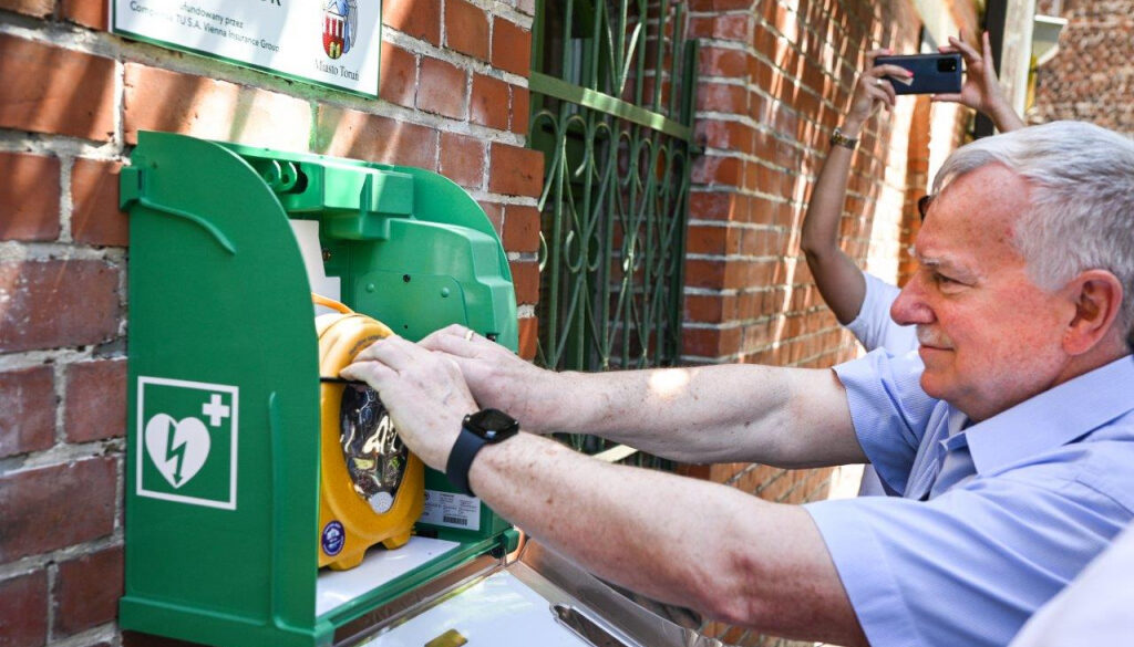 Zbigniew Fiderewicz zastępca prezydenta Torunia pokazuje defibrylator, zamontowany na budynku Urzędu Miasta Torunia