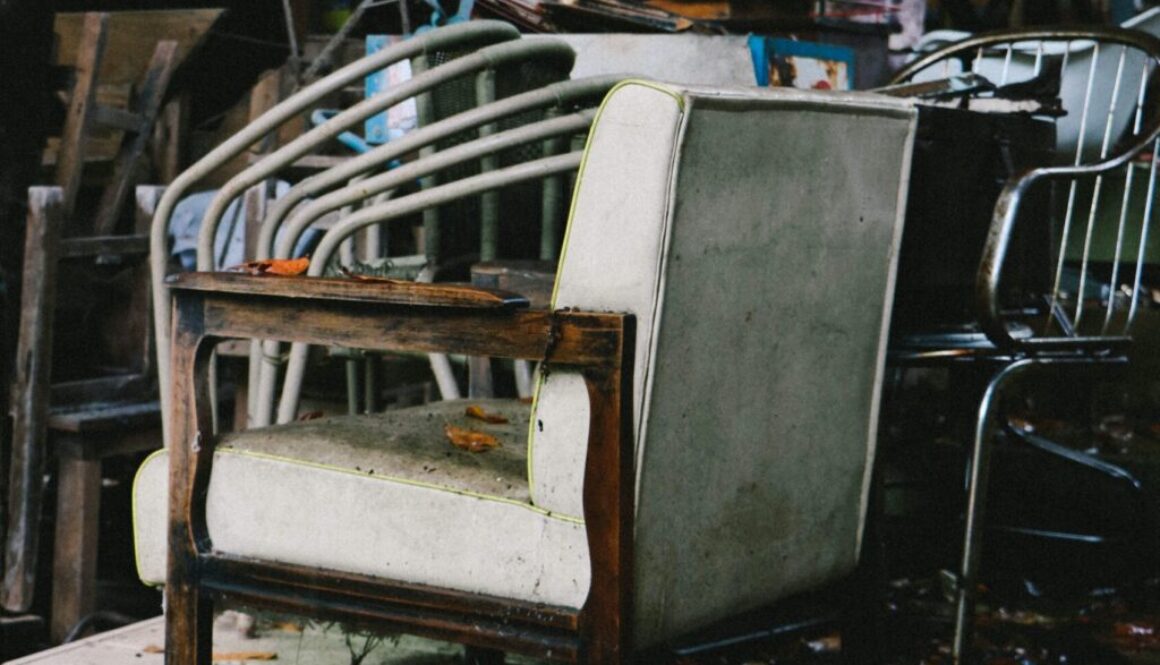 Stary zniszczony fotel z białą tapicerką