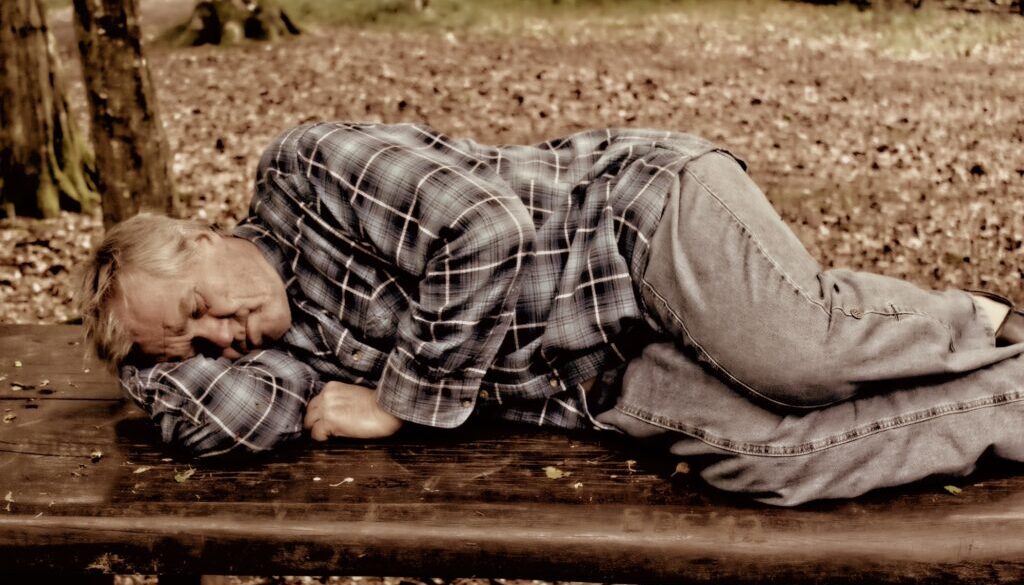 Bezdomny mężczyzna leżący na ławce