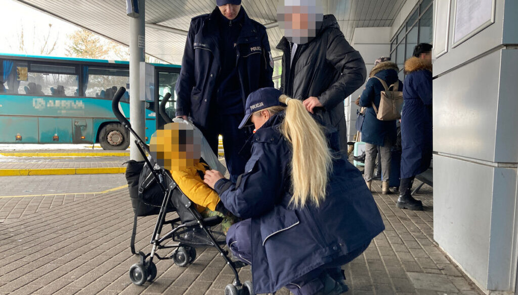 Policjantka opiekuje się dzieckiem w wózku na dworcu autobusowym