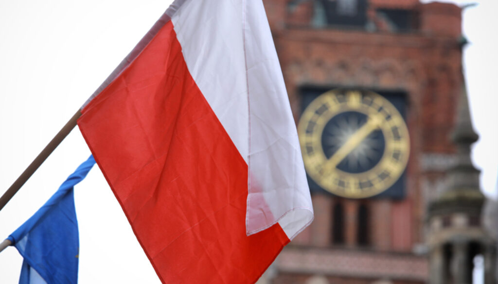 Biało-czerwona flaga na tle toruńskiego ratusza