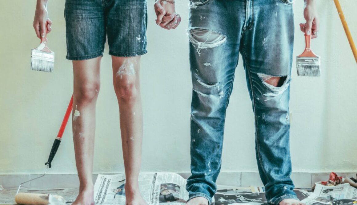 Dwójka osób w roboczych ubraniach z pędzlami w dłoni podczas remontu mieszkania