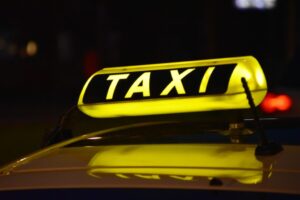 Zbliżenie na tabliczkę z napisem "taxi", zainstalowaną na dachu samochodu
