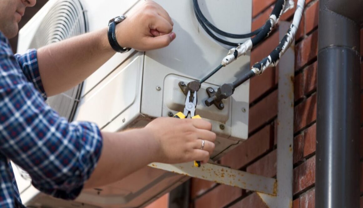 Closeup photo of male technician repairing outdoor air conditioner unit